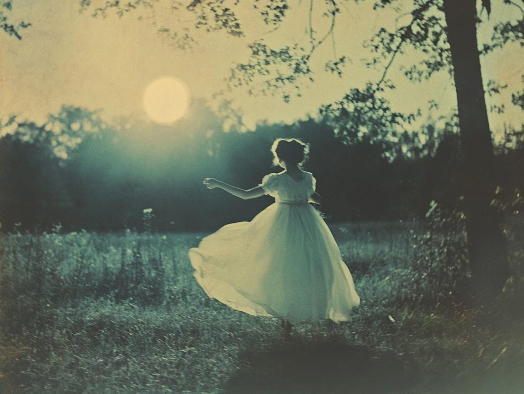 Vintage photo of a single person performing a silly dance under a full moon, wide shot