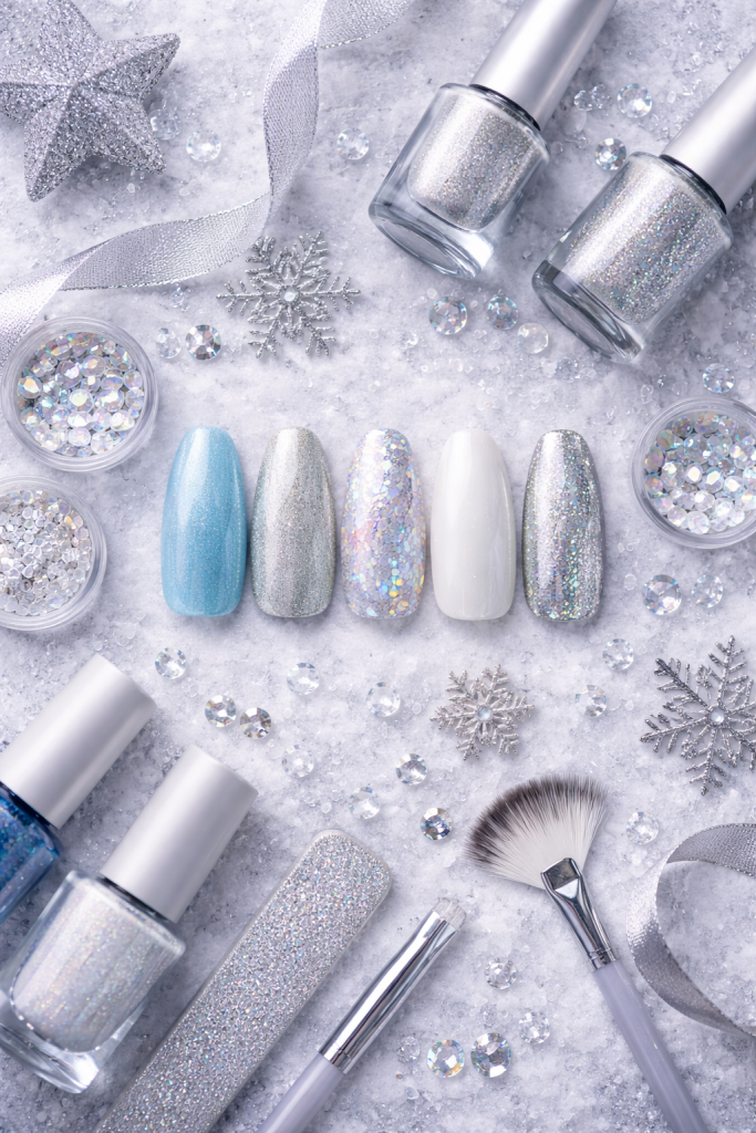 Winter nail art essentials flat lay with polishes, glitter, brushes, and nail tips.