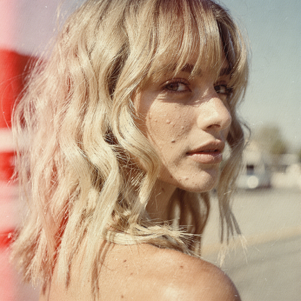 Shoulder-length sandy blonde shag with curtain bangs