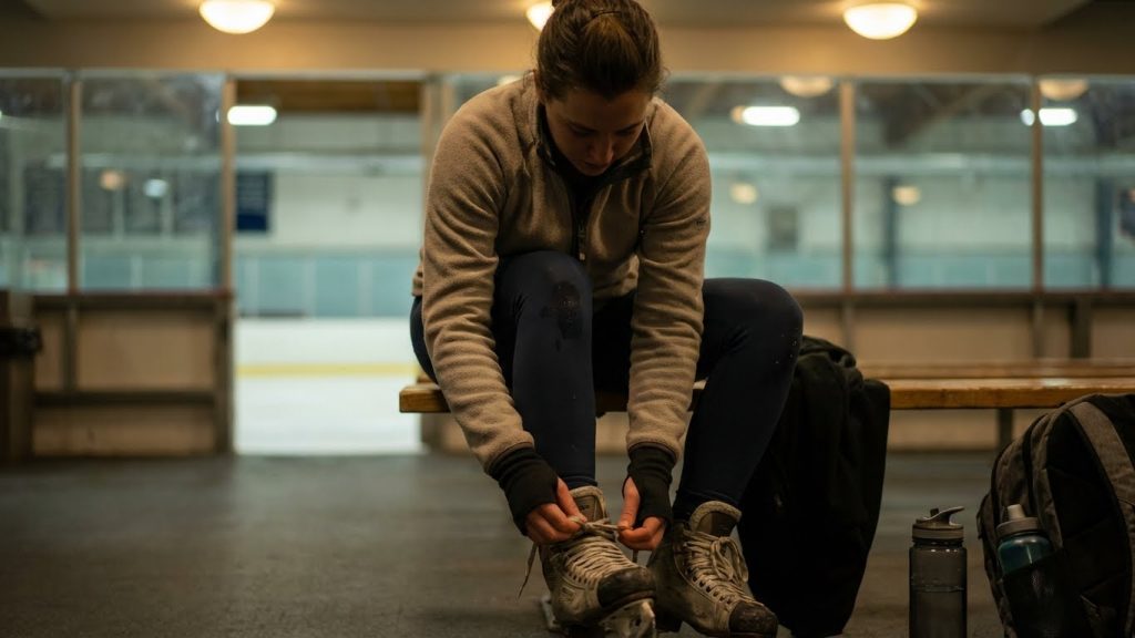 Woman in fleece jacket and leggings tying ice skates post-skating.