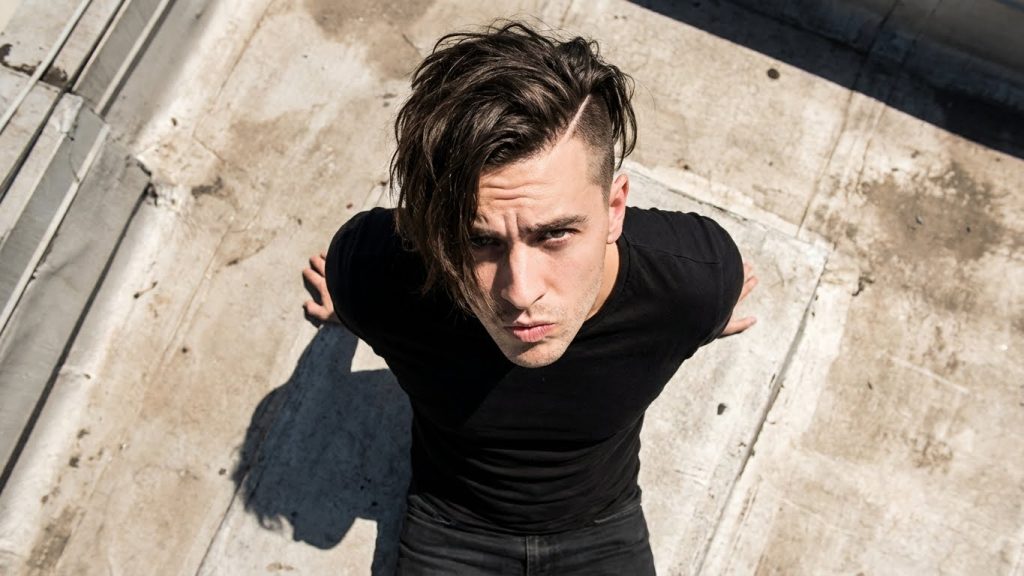 Men's undercut hairstyle, medium length messy top, dark hair, urban background