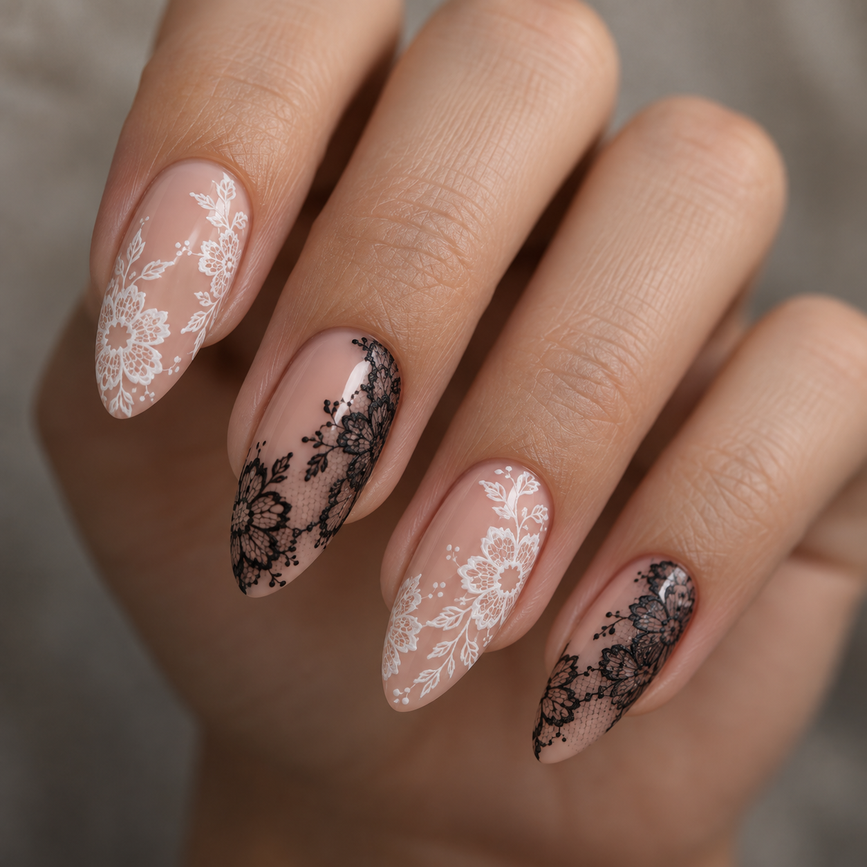 Almond nails with nude base feature alternating white and black lace floral nail art designs on a glossy finish.