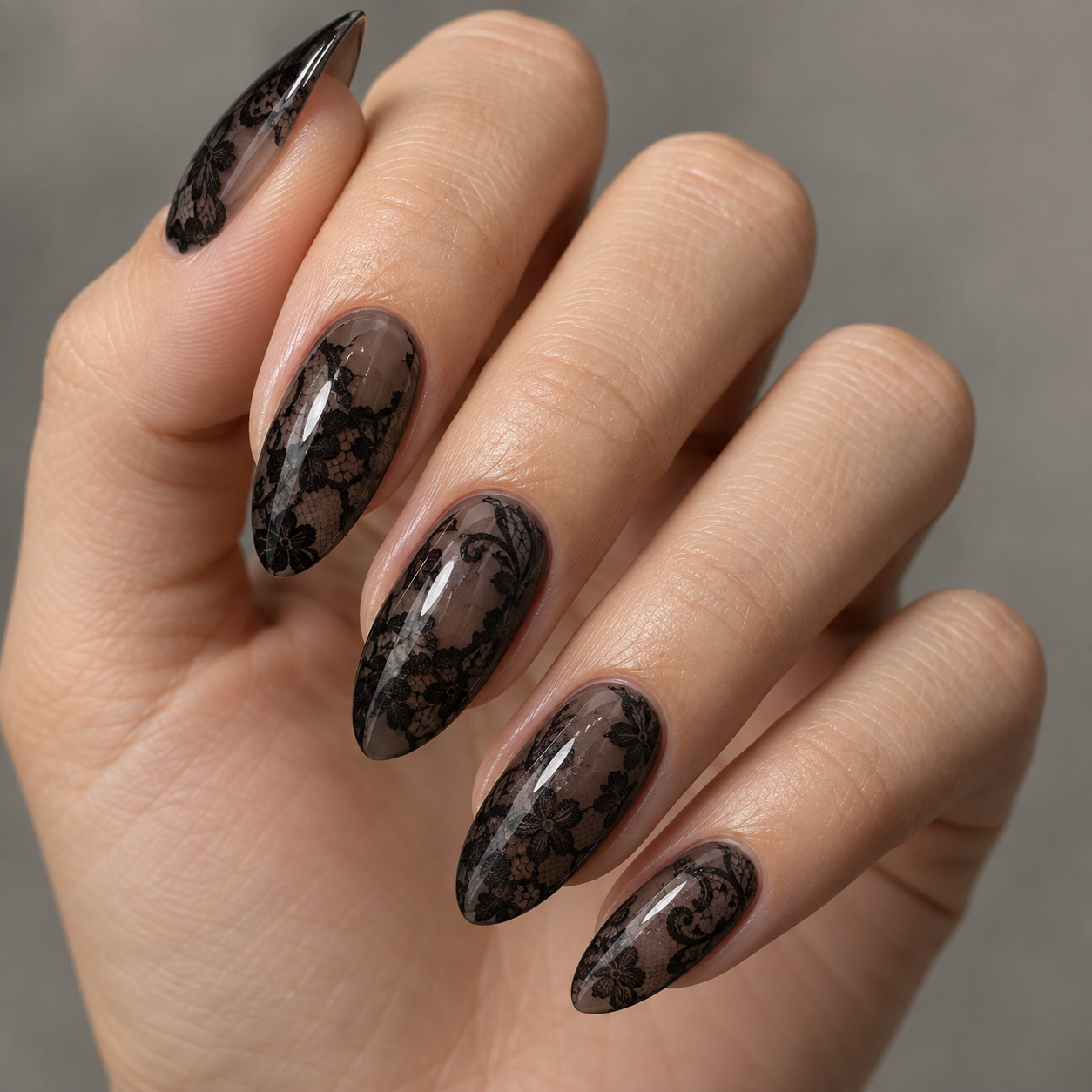 Glossy smoky sheer black nails with darker black floral lace patterns.