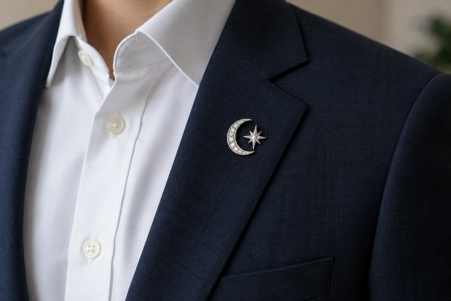 Silver crescent moon and star brooch on a navy lapel.