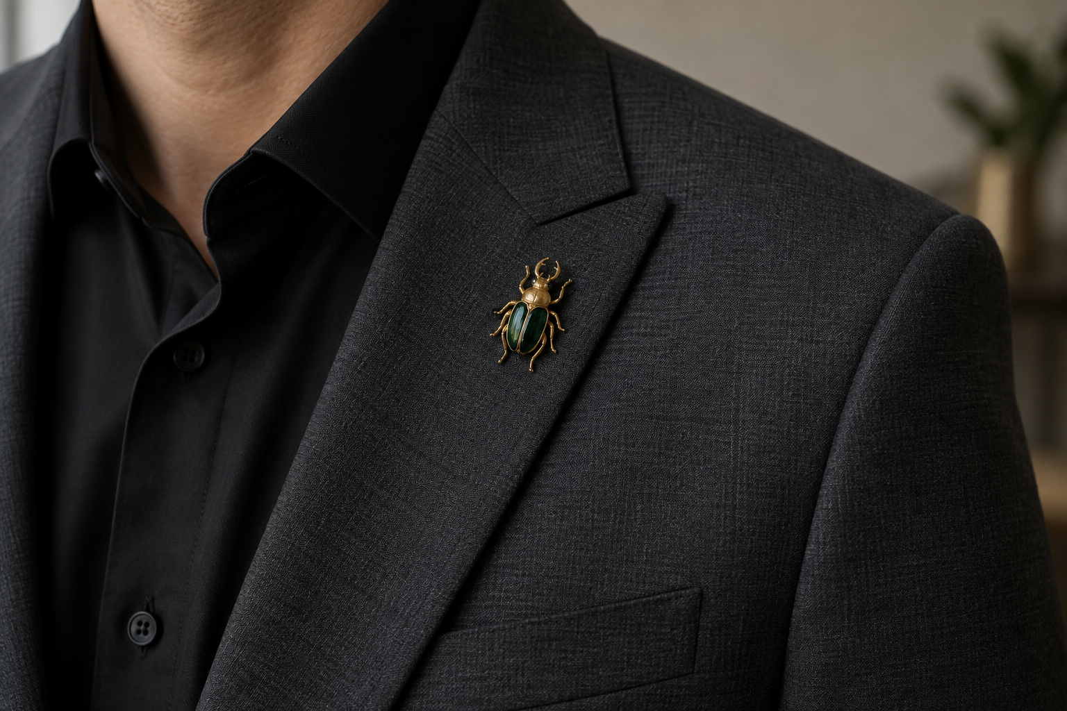 Gold and emerald beetle brooch high on a charcoal lapel.