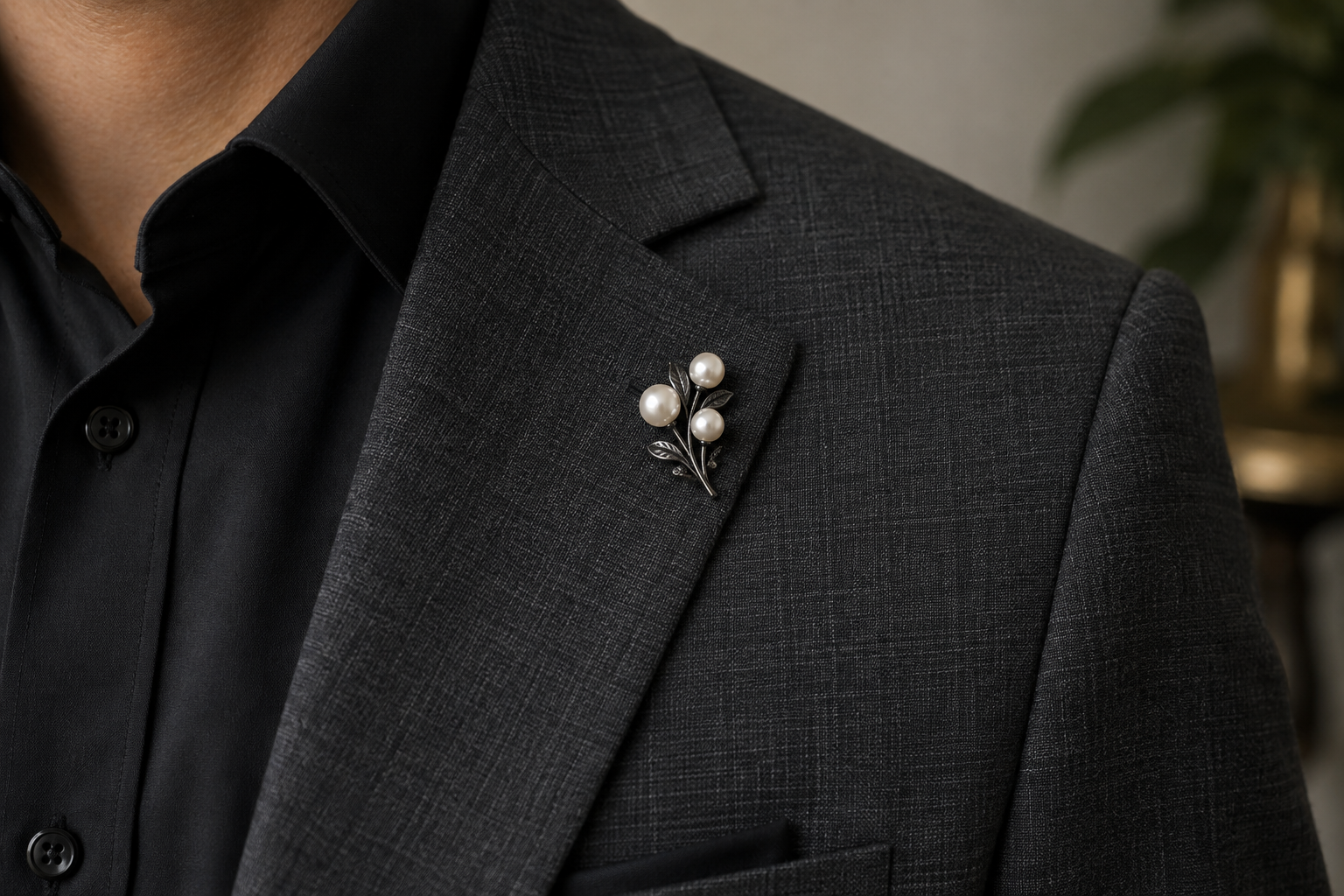 Cream pearl brooch in a dark metal setting on charcoal wool.