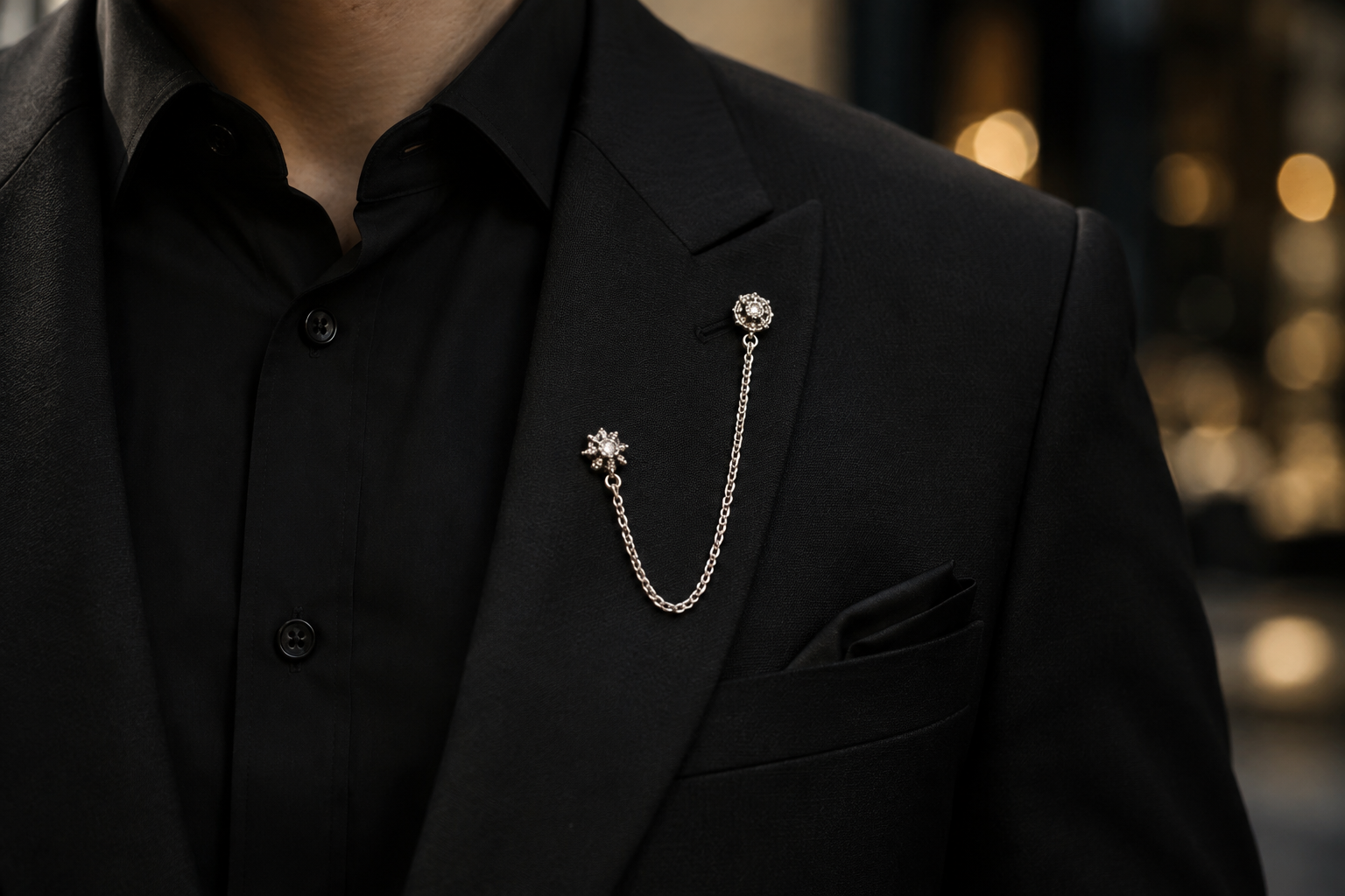 Silver chain linking two decorative pins on a black suit lapel.