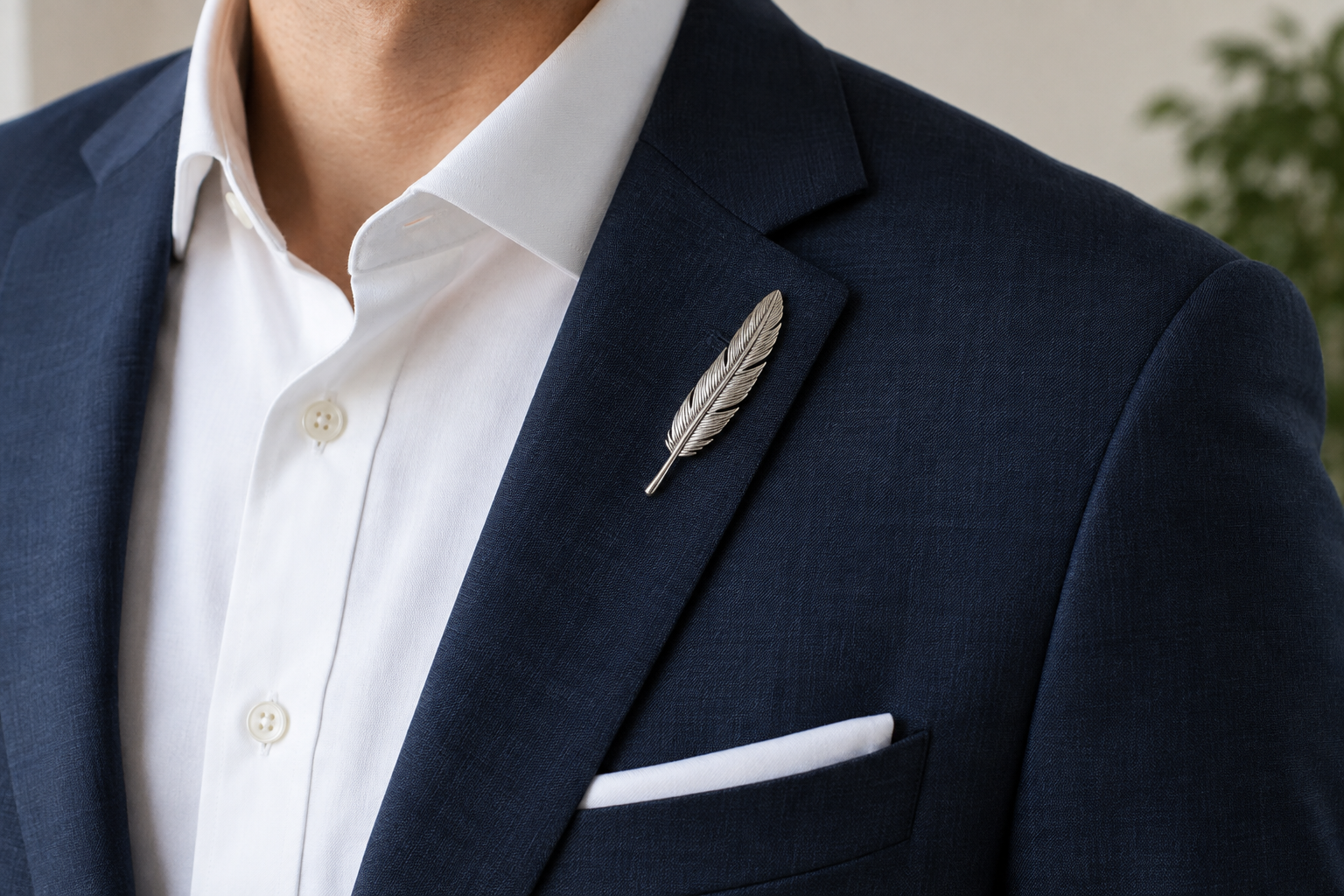 Silver feather brooch following the angle of a navy suit lapel.
