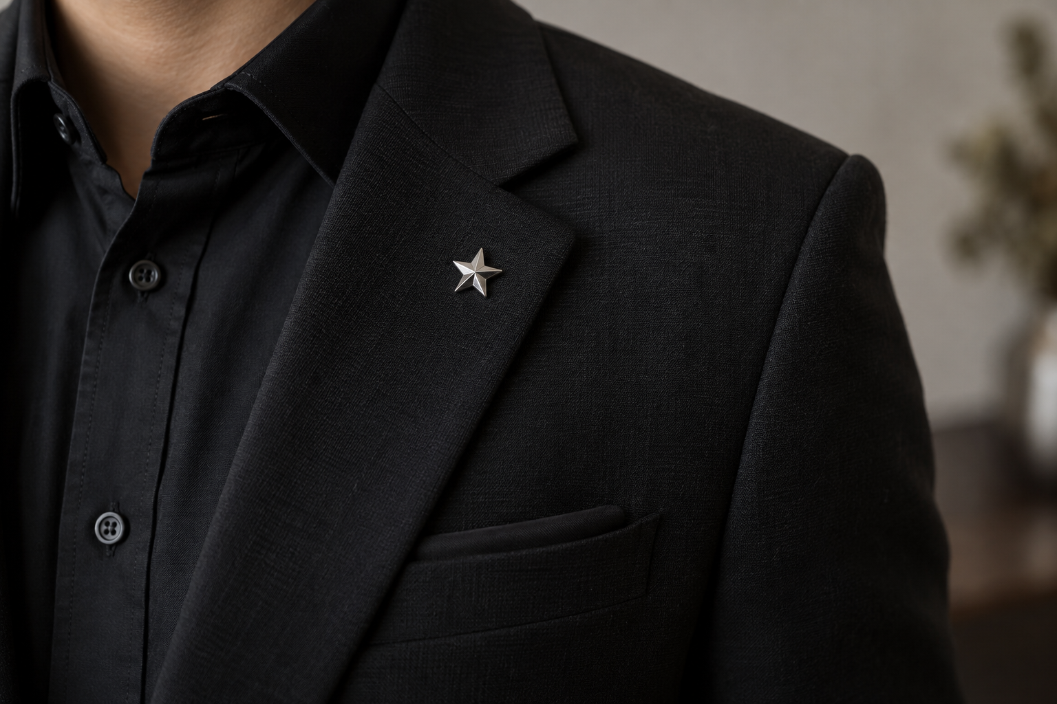 Small silver star brooch on a black suit lapel.
