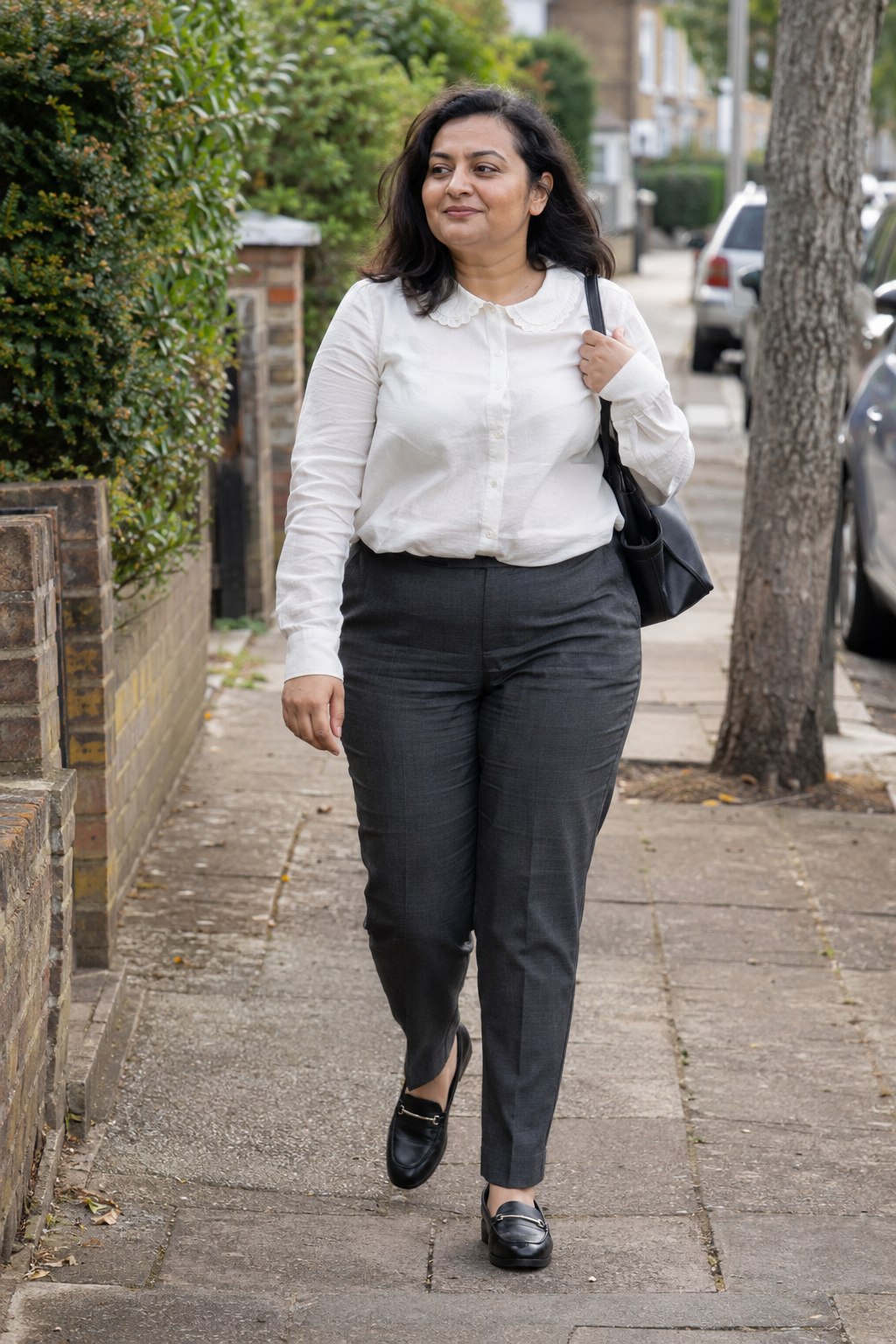 Woman in an ivory blouse with a small scalloped collar, charcoal trousers and black loafers.