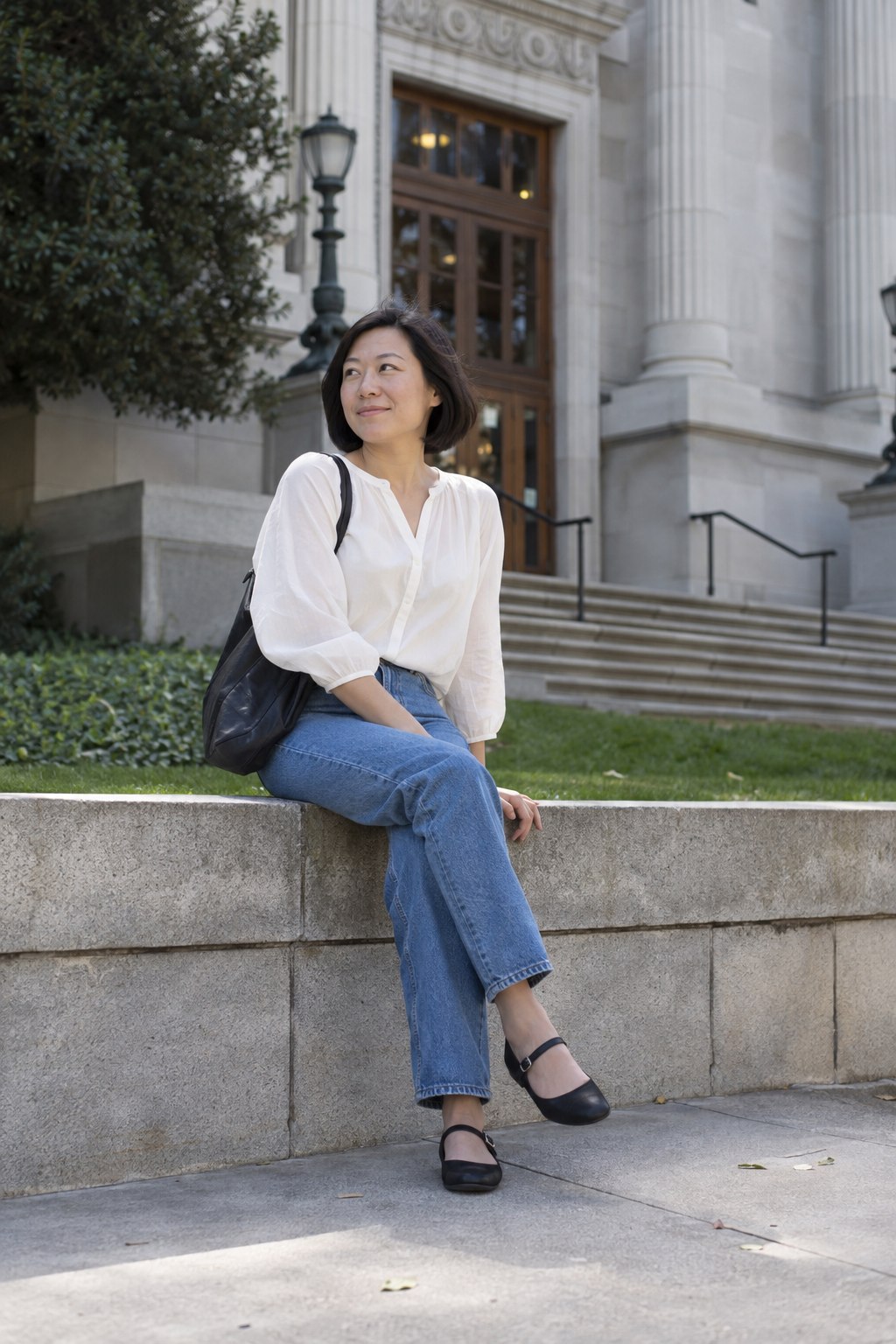 Woman wearing black Mary Jane flats with ankle-length jeans and an ivory cotton blouse.