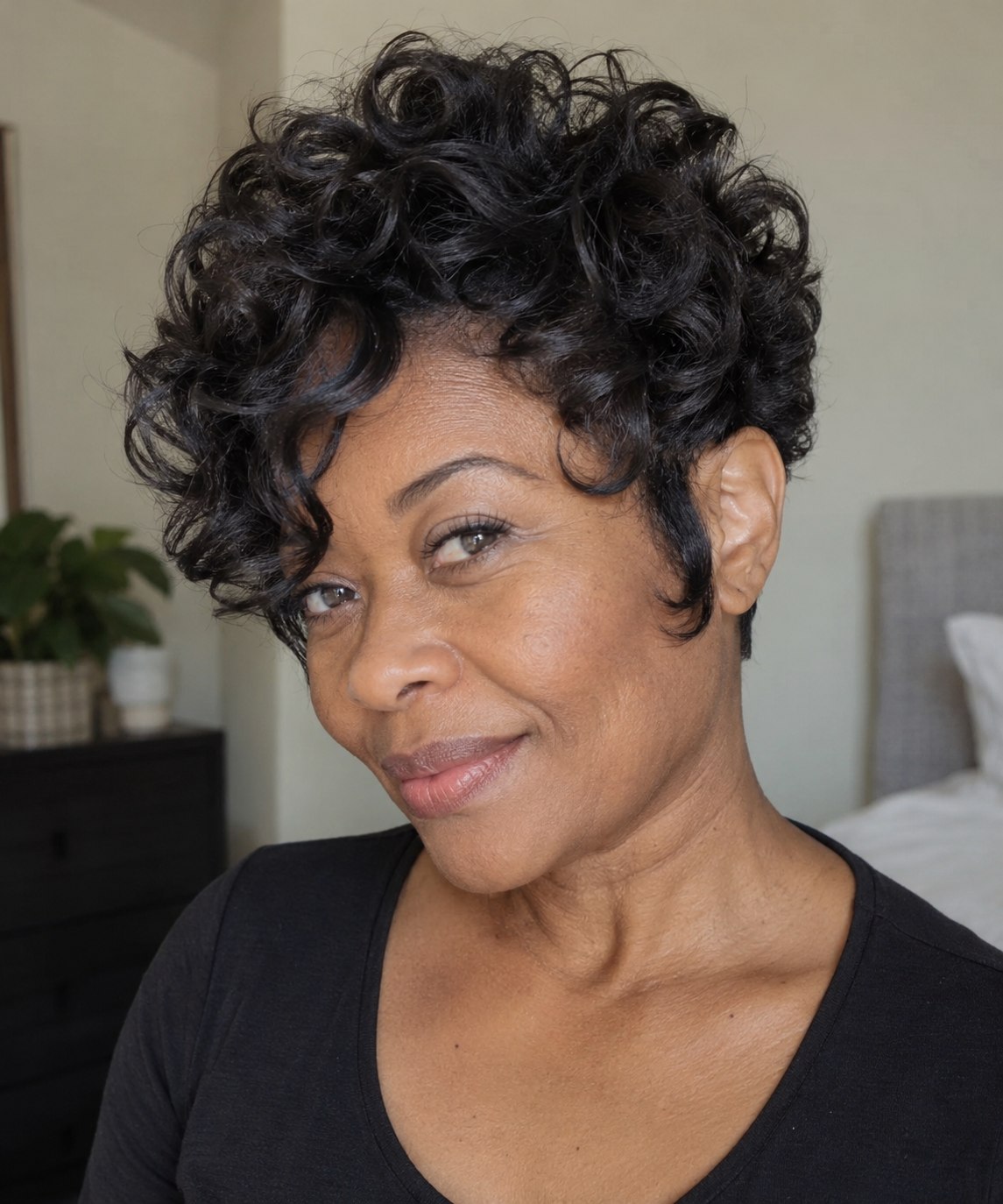 Rounded dark pixie with a soft crown, a longer cheek-framing piece and an exposed opposite ear.