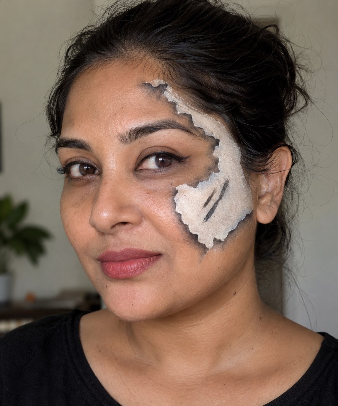 Halloween makeup showing a jagged white paper-like patch on one cheek with gray painted shadows.
