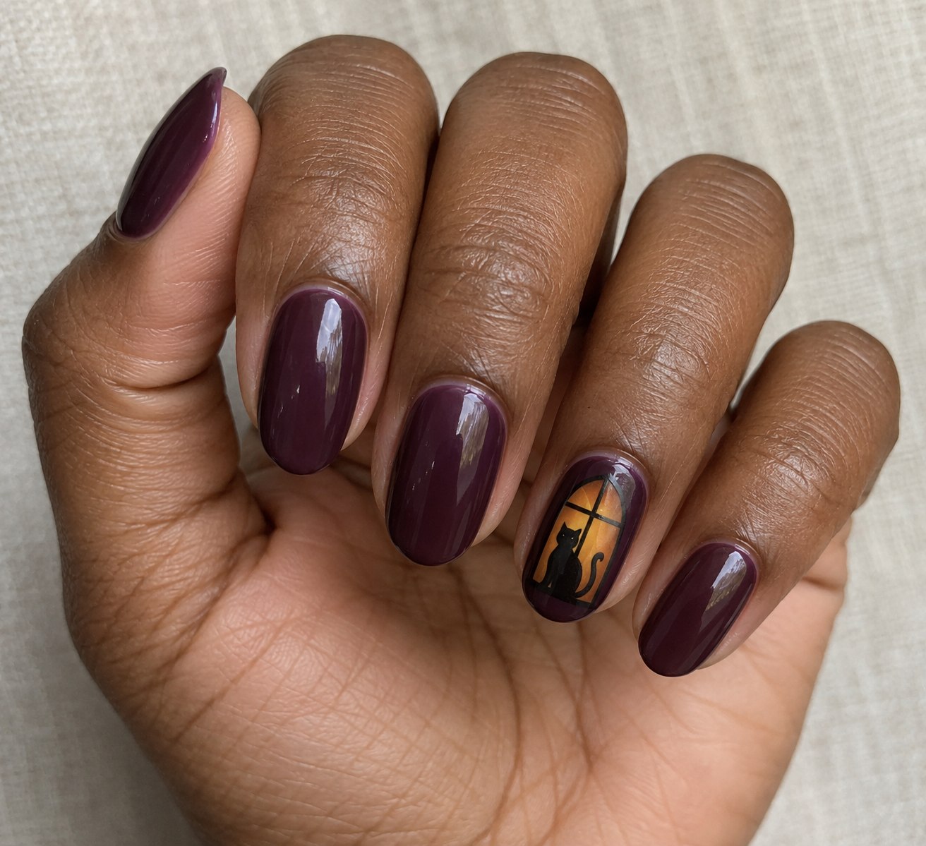 Plum nails with a black cat silhouette inside a small amber attic window