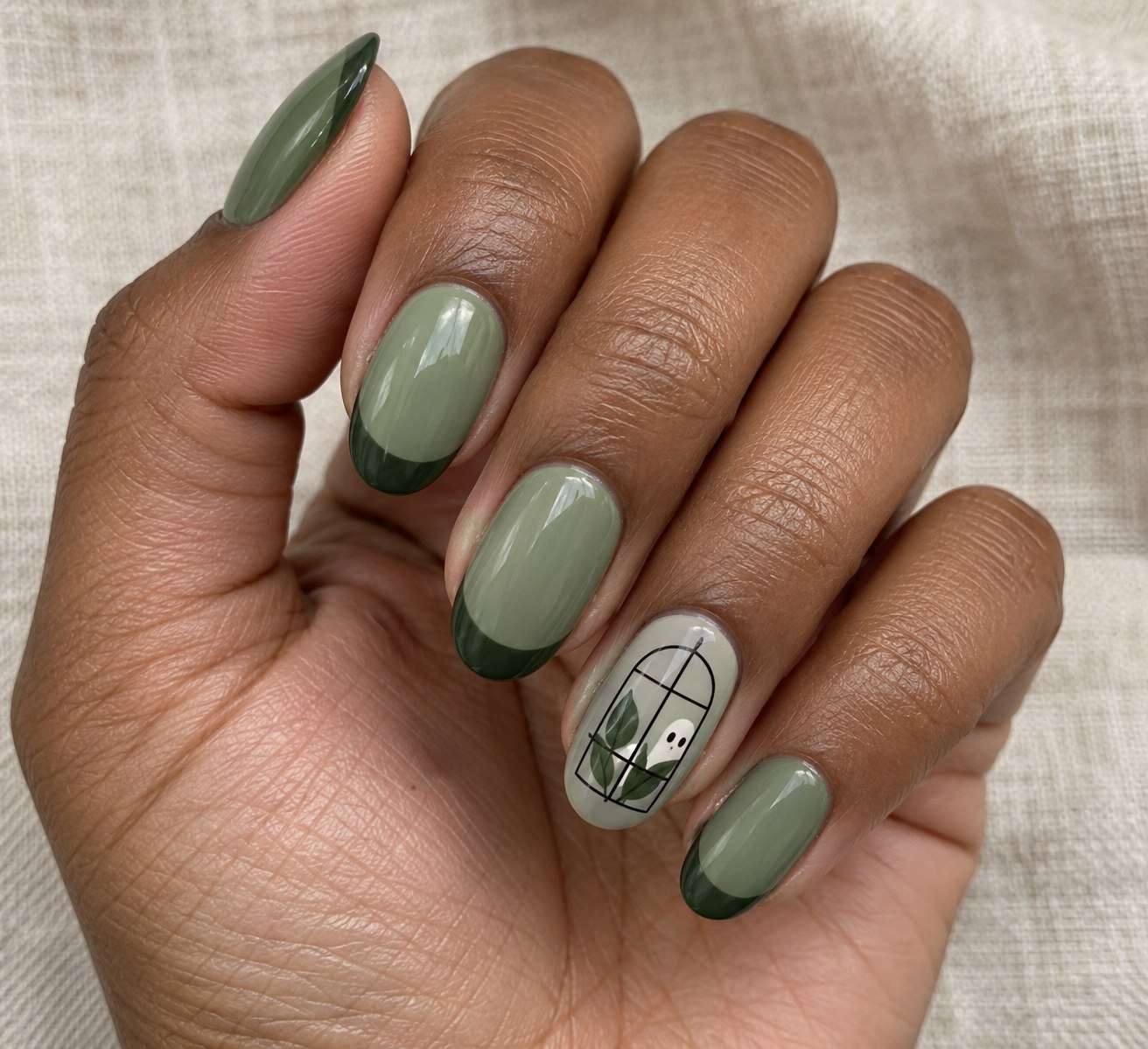 Sage Halloween nails with a tiny ghost behind a greenhouse window on an accent nail