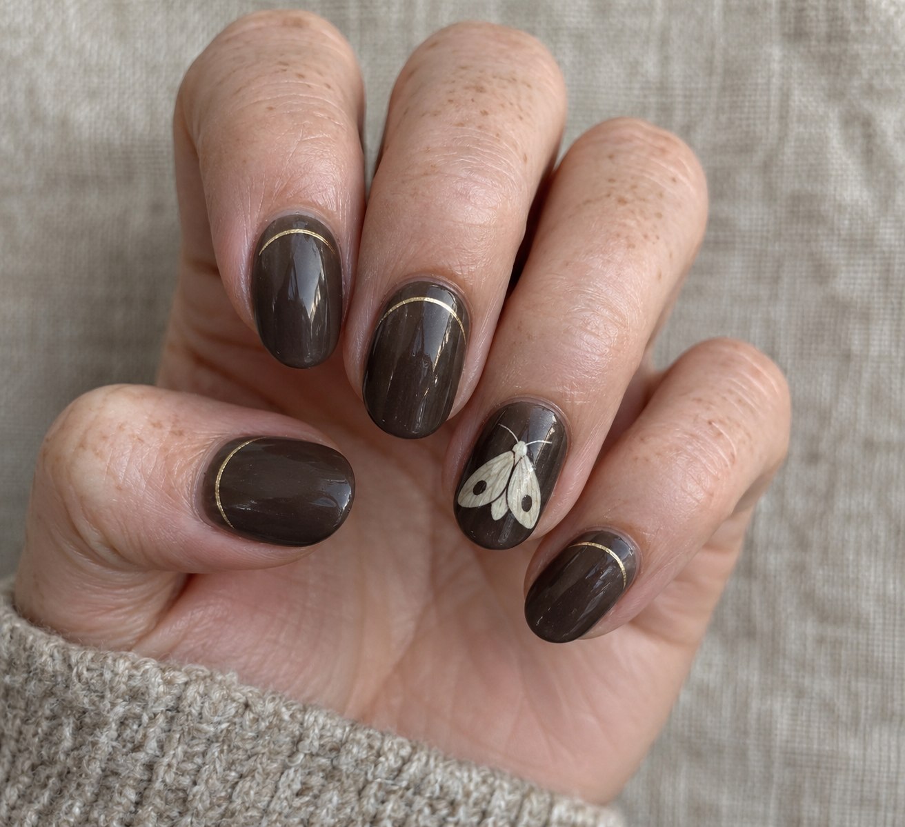 Smoky cocoa nails with a cream moth and delicate gold cuticle arcs