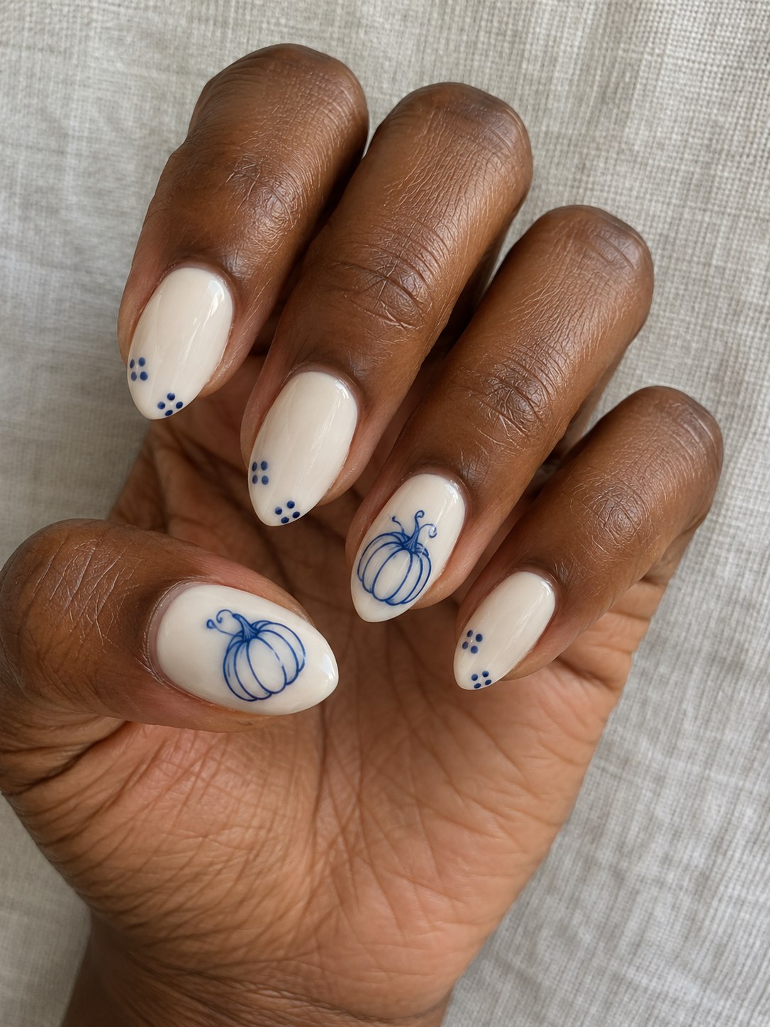 Ivory almond nails with cobalt blue pumpkin outlines and small blue decorative dots