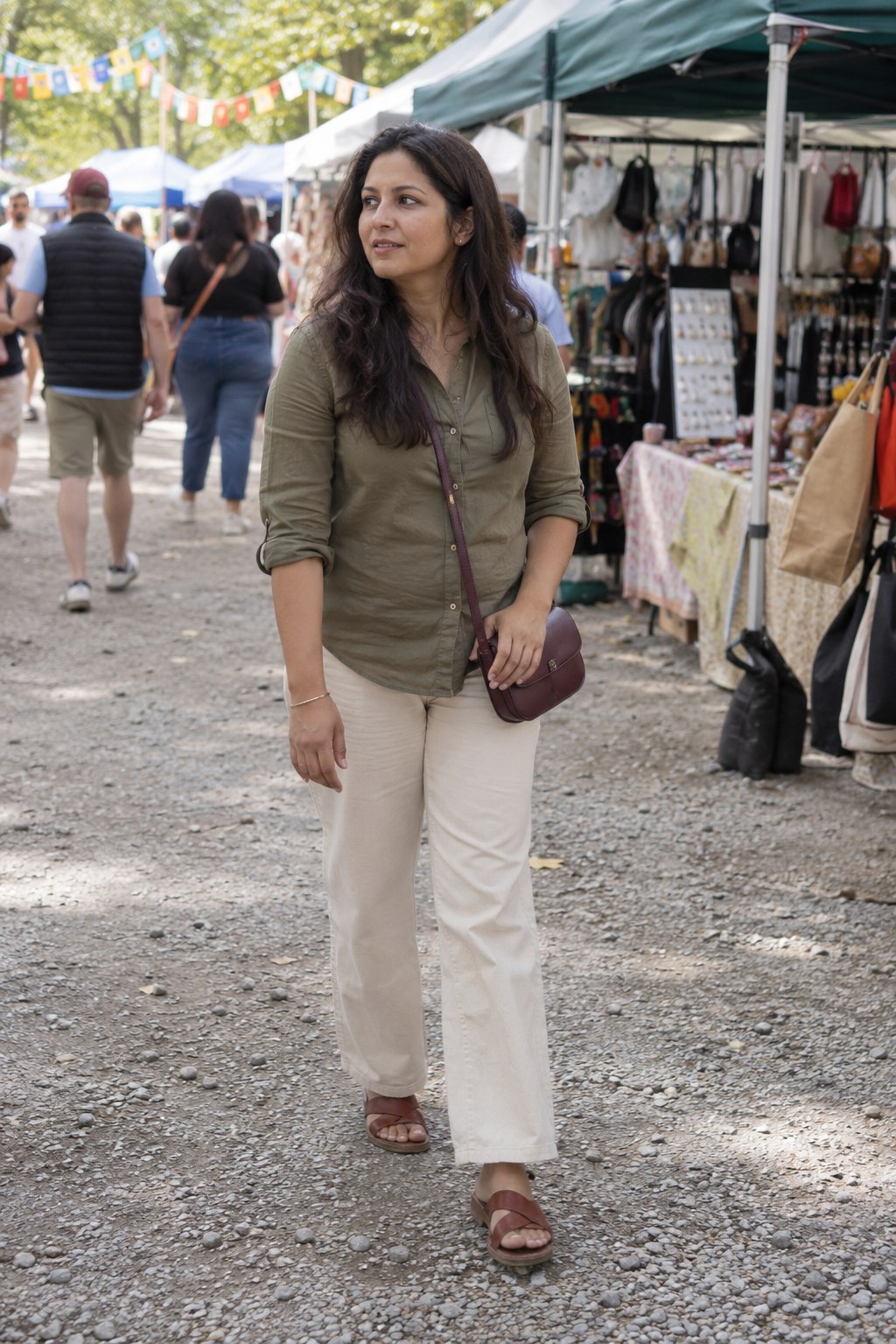 Small plum crossbody bag with an olive shirt and ecru trousers.