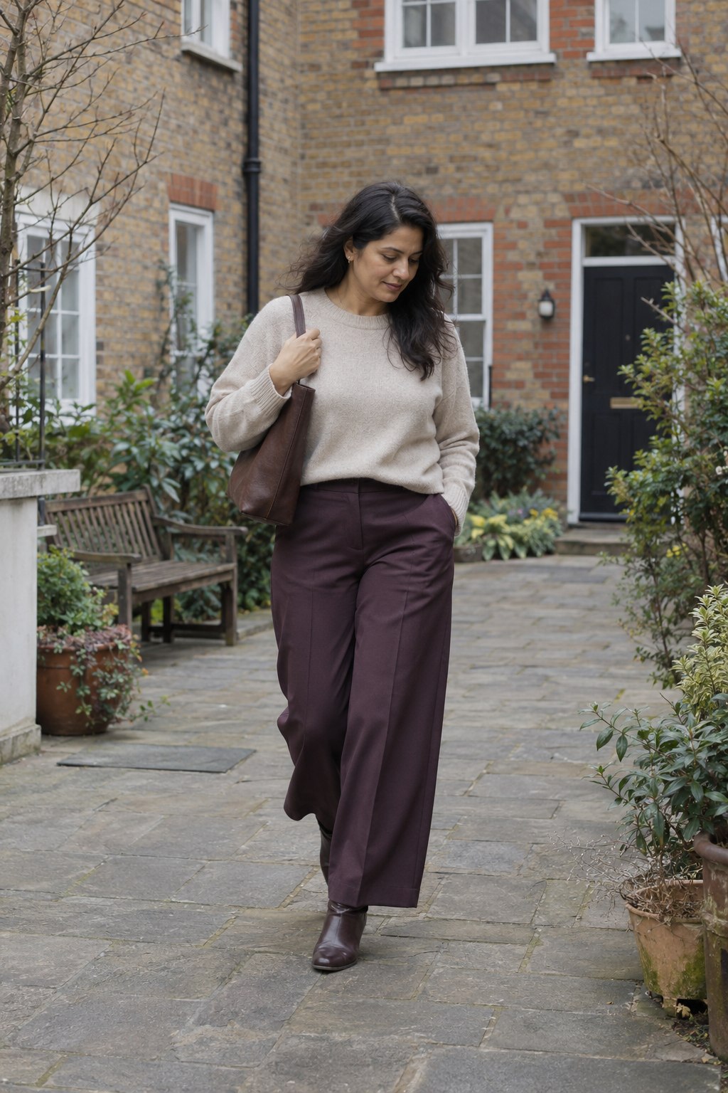 Dark plum wide-leg trousers paired with an oatmeal sweater and brown boots.
