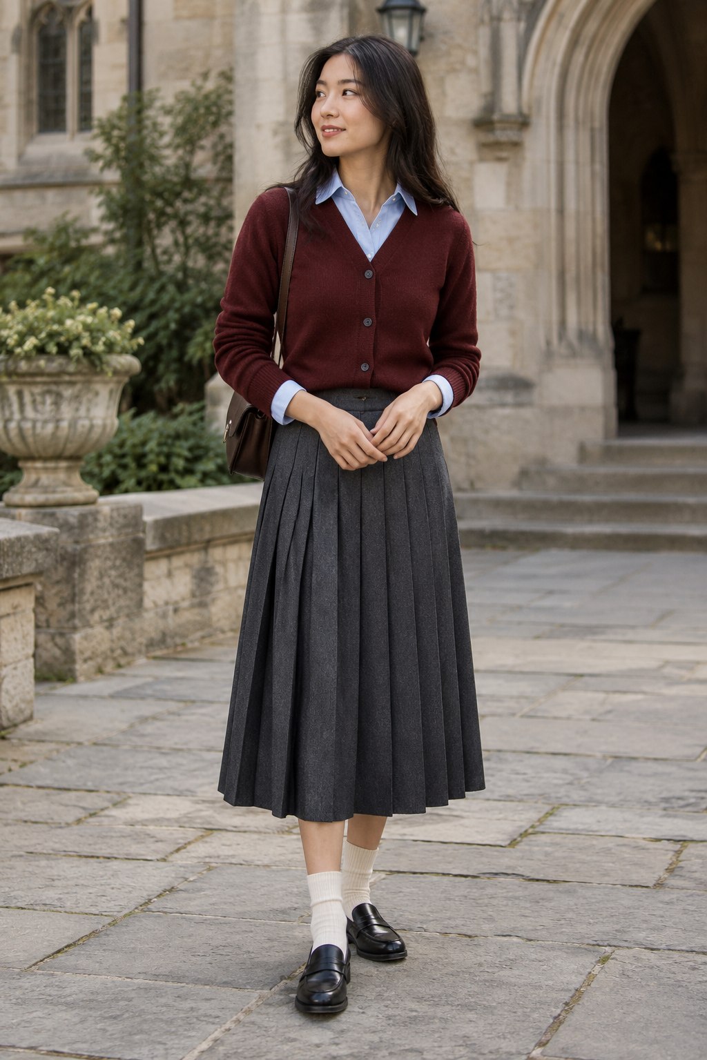 Burgundy cardigan layered over a blue shirt with a charcoal pleated skirt and loafers.
