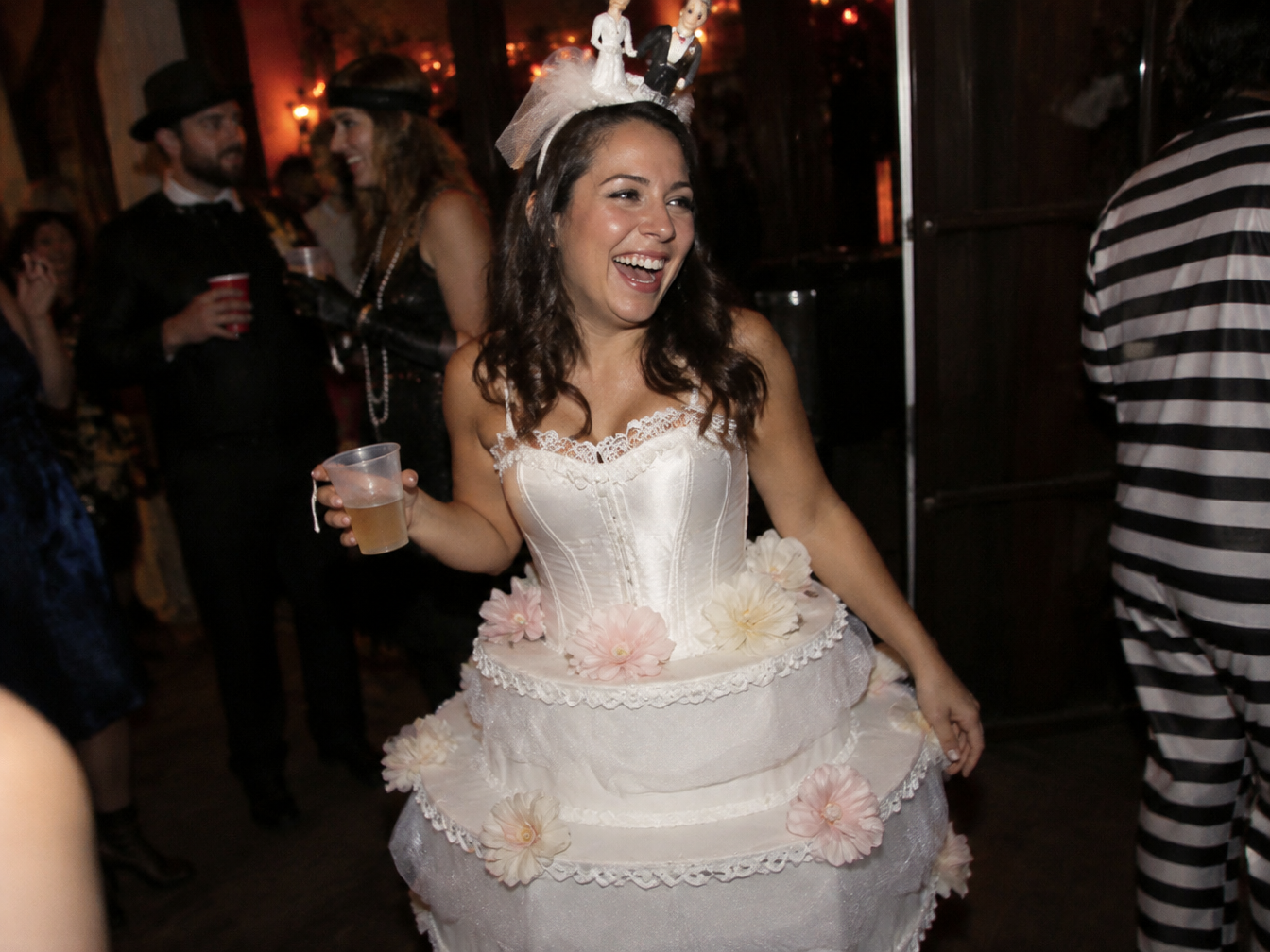 Woman laughing in a wedding cake costume with a white corset top and tiered tulle skirt