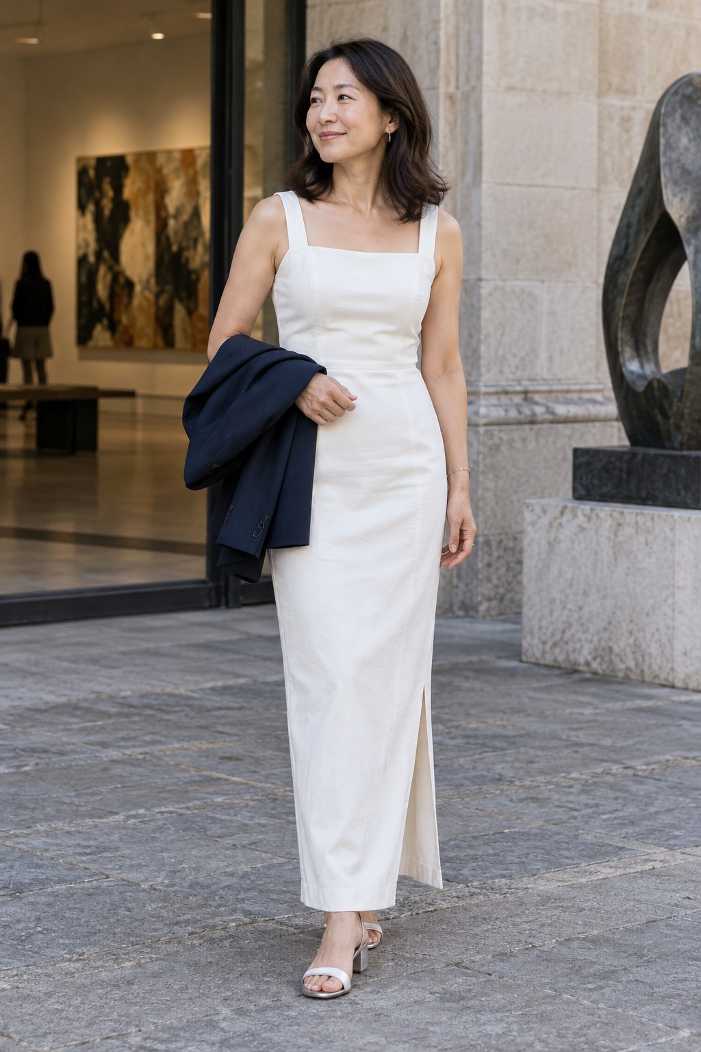 Long white column dress with a square neckline, pale heeled sandals and a navy blazer